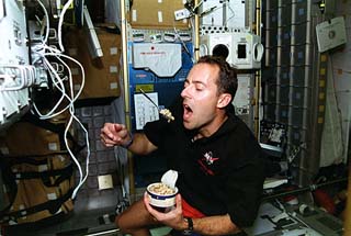 Mission specialist Jean-Francois Clervoy eating in the Spacehab.